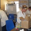 Laboratory with three individuals in white lab coats working at different stations.