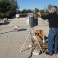 Man adjusting weather monitoring equipment on a rooftop.