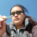 Person wearing sunglasses holding a pen against a clear blue sky.