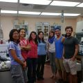 A group of seven people standing in a laboratory, smiling at the camera.