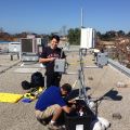 Two people on a rooftop working with technical equipment in a sunny setting.