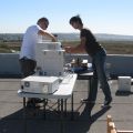 Two individuals assembling electronic equipment on a rooftop.