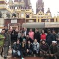 Group of people posing in front of an ornate building with Hindu architectural elements.