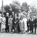 Black-and-white photograph of fifteen people standing on a lawn, dressed in formal attire.