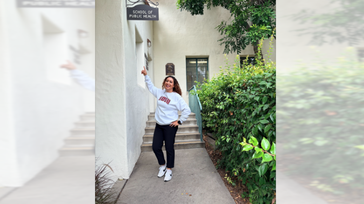 Student pointing at the Doctor of Public Health Sign on a building.