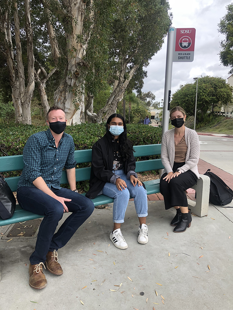 Students sitting on bench with masks on