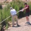 two researchers by a riverbed removing items from the water